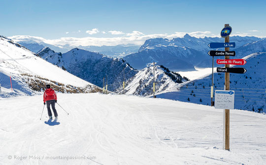 Skier starting Lac piste with mountain scenery above Praz de Lys, French Alps.