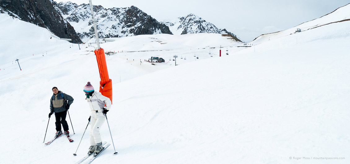 Skiers beside snow cannon at La Mongie, Grand Tourmalet, French Pyrenees