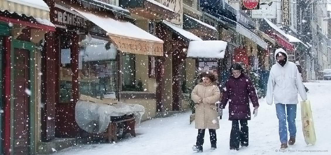 Family in falling snow at Le Mont Dore ski village, Auvergne, France.