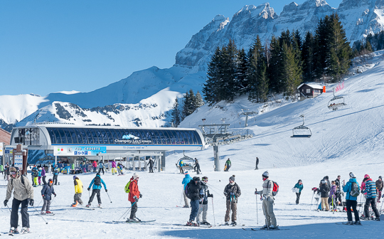 Skiers around big chairlift in wide valley at Les Crozets