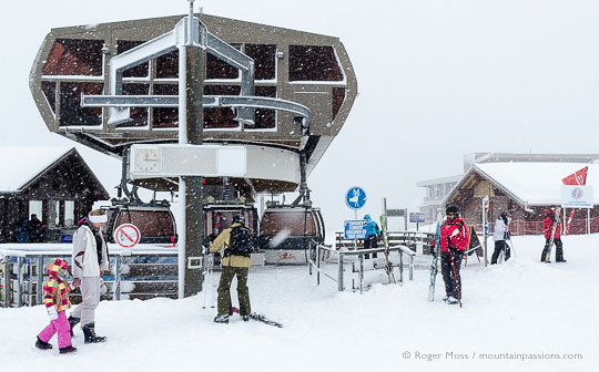 Skier beside gondola lift in falling snow at Samoens 1600, French Alps.