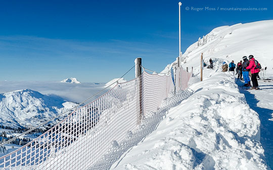 Skiers overlooking ski terrain from snow-covered ridge at Tete de Linga, Chatel