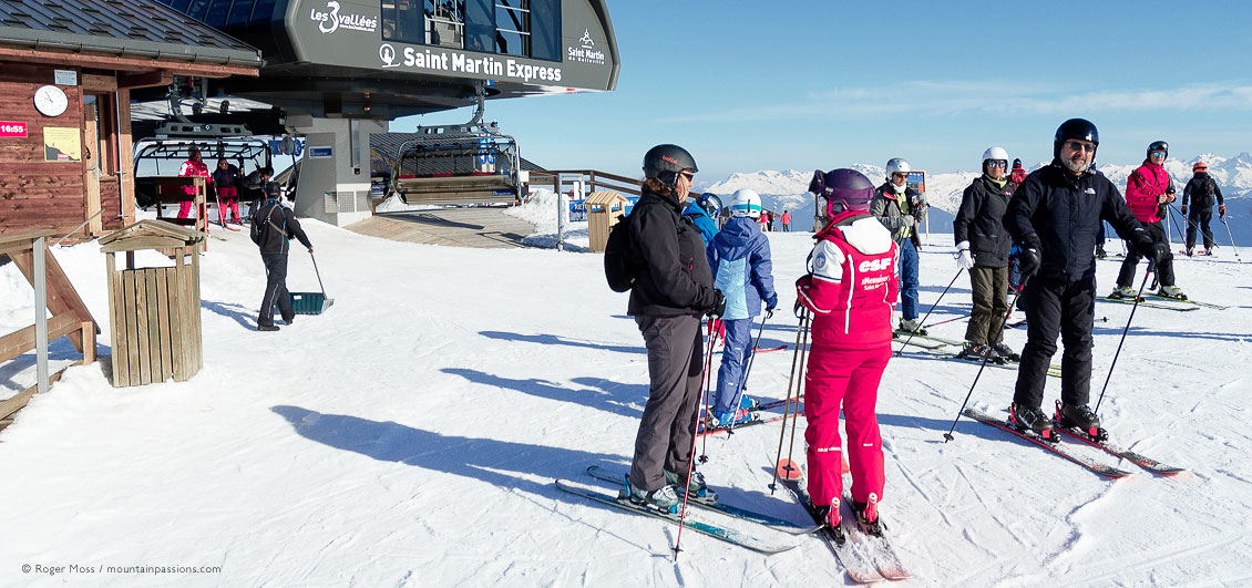 Skiers and ski instructor beside chairlift above Saint Martin de Belleville