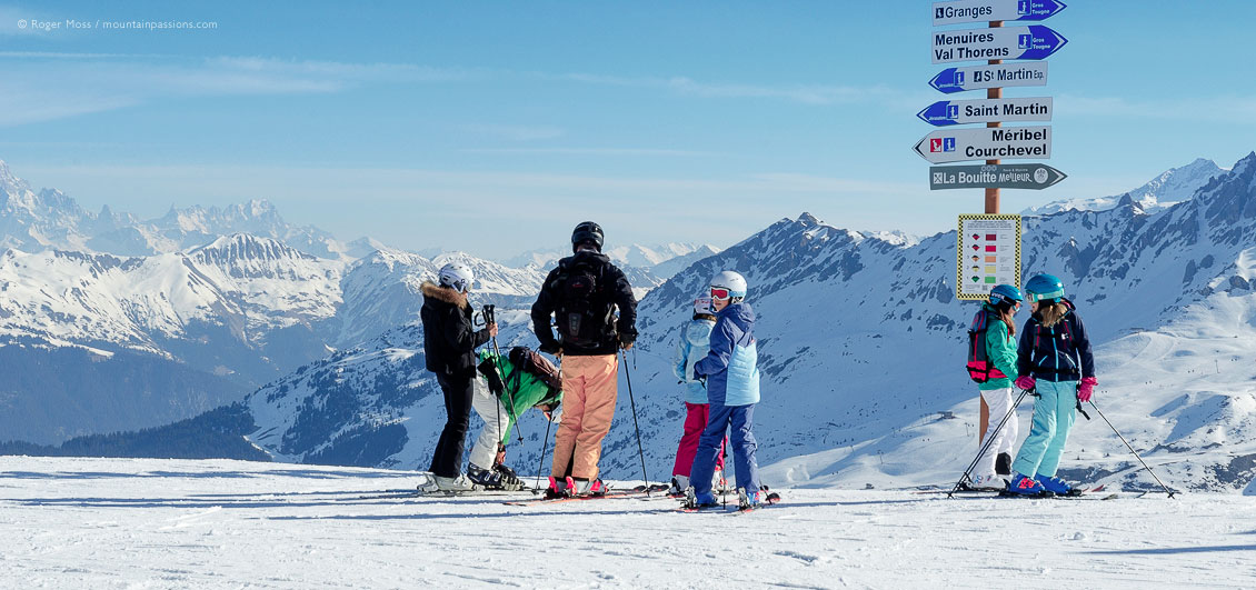 Skiers beside sign with mountains