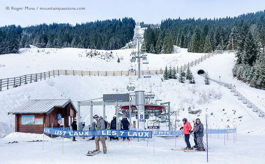 skiers joining chairlift at Le Pleynet, with snow-covered mountains