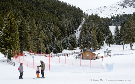 Grandparents with young child skier in debutant area with ski lift