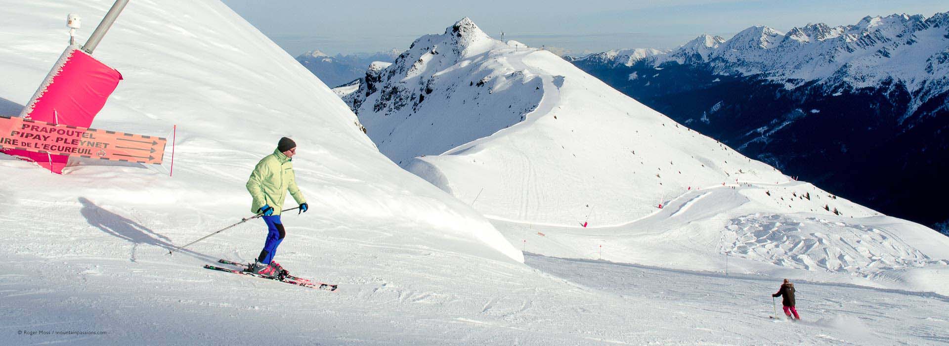 Skiers on piste with wide mountain view