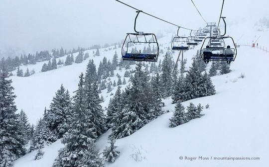 View from chairlift of mountainside with falling snow